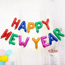 a bunch of colorful happy new year balloons hanging on a wall