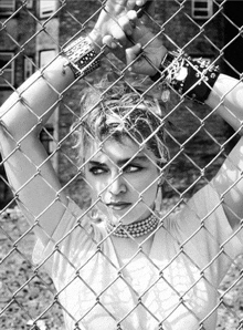 a woman behind a chain link fence wearing bracelets that say " i love you "