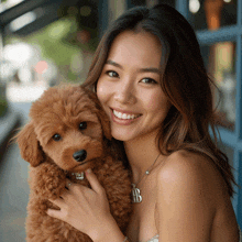 a woman is holding a small brown poodle with a necklace that says ab