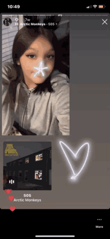 a phone screen shows a girl with a star on her face and arctic monkeys on the bottom