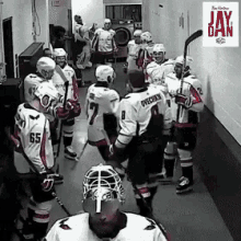 a group of hockey players are standing in a hallway with a jay day logo on the wall behind them