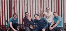 a group of young men are posing for a picture in front of a red and white striped fence .