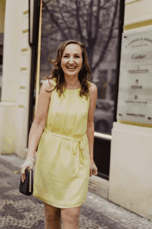 a woman in a yellow dress stands in front of a building that says cartier