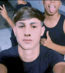 a young man sticking his tongue out while taking a selfie with his friends