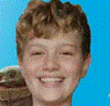 a close up of a young boy 's face smiling with a blue background .