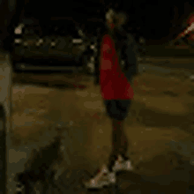 a person in a red shirt and shorts is standing in a puddle of water .