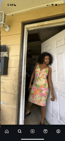 a woman in a floral dress is standing in a doorway next to a sign that says blessing