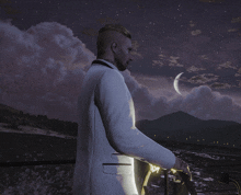 a man in a white tuxedo stands on a balcony overlooking the ocean at night