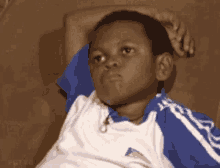 a young boy in a blue and white shirt is sitting on a couch .