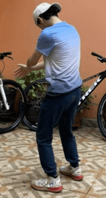 a man in a blue shirt and white hat is standing next to a bicycle .