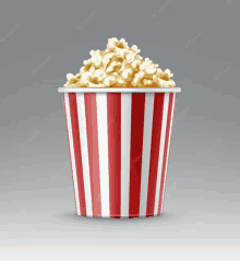 a striped bucket filled with popcorn on a gray background