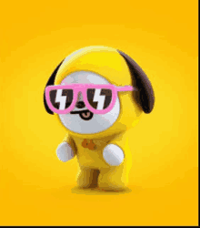 a yellow stuffed animal wearing pink sunglasses and a bow tie on a yellow background .