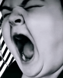 a close up of a person yawning with their eyes closed