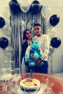 a boy and a girl pose in front of a birthday cake that says feliz cumpleaños