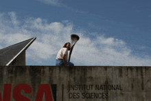 a woman sitting on top of a wall with the word institut national des sciences on it