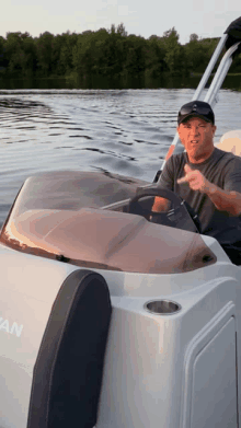 a man is driving a boat on a lake and giving the middle finger