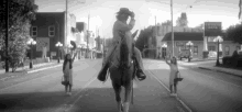 a black and white photo of a man riding a horse down a street in front of a building that says stephens bank