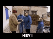 a group of people are standing next to each other in front of a pile of dirt and a sign that says hey !