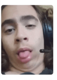 a man wearing headphones is sticking his tongue out while making a funny face .