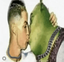 a man is kissing shrek who is wearing a chain around his neck