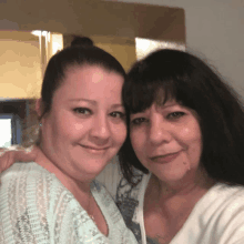 two women posing for a picture with one wearing a blue shirt