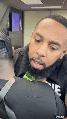 a man with a beard wearing a black shirt that says creative comedy on it