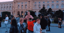 a group of people standing in front of a large building with a sign that says ' a ' on it