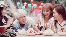 a group of girls are sitting at a table with plates of food and rainbow written on the bottom right corner