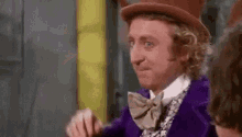 a man in a purple suit and top hat is making a face .