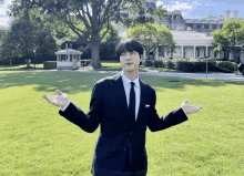 a man in a suit and tie is standing in front of a white house