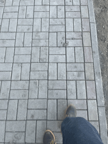 a person standing on a brick sidewalk with their feet visible