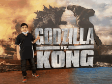 a young boy is standing in front of a poster for godzilla vs kong