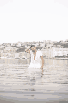 a man in a white shirt is standing in the water with his hand on his head