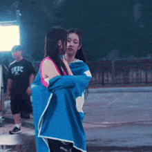 a woman is wrapped in a blue towel while another woman stands behind her