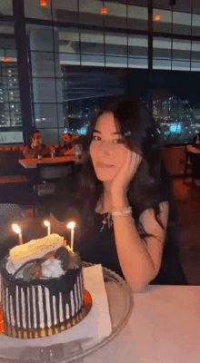 a girl is sitting at a table with a birthday cake