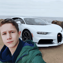 a young man taking a selfie in front of a bugatti car