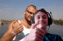 a boy wearing headphones giving a thumbs up in front of a man