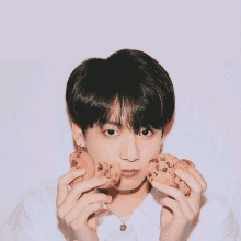 a young boy is holding two chocolate chip cookies in his hands