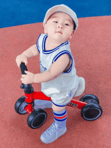 a baby wearing a white shirt that says love is riding a red bike