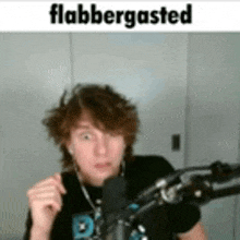 a young man is standing in front of a microphone with a caption that says flabbergasted .