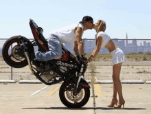 a man and a woman are kissing while standing next to a motorcycle .