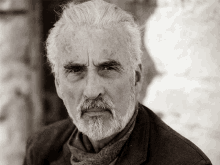 a man with gray hair and a beard is wearing a scarf