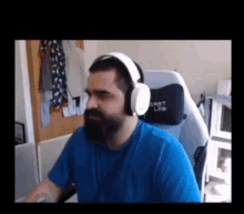 a man with a beard is wearing headphones and sitting in a chair .