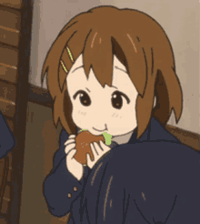 a girl in a school uniform is eating a sandwich