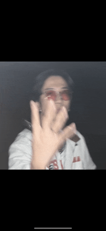 a blurry picture of a person wearing red sunglasses making a peace sign