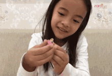 a little girl is playing with a toy in front of a wall with flowers and the word zorocute on it