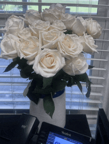 a bouquet of white roses in a vase next to a yealink phone