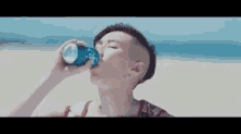 a woman is drinking from a blue can on the beach .