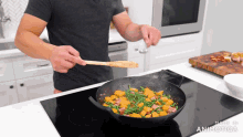 a man is stirring vegetables in a frying pan with a wooden spoon and the words made in animotica visible