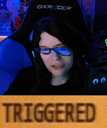 a woman wearing glasses is sitting in a dxracer gaming chair